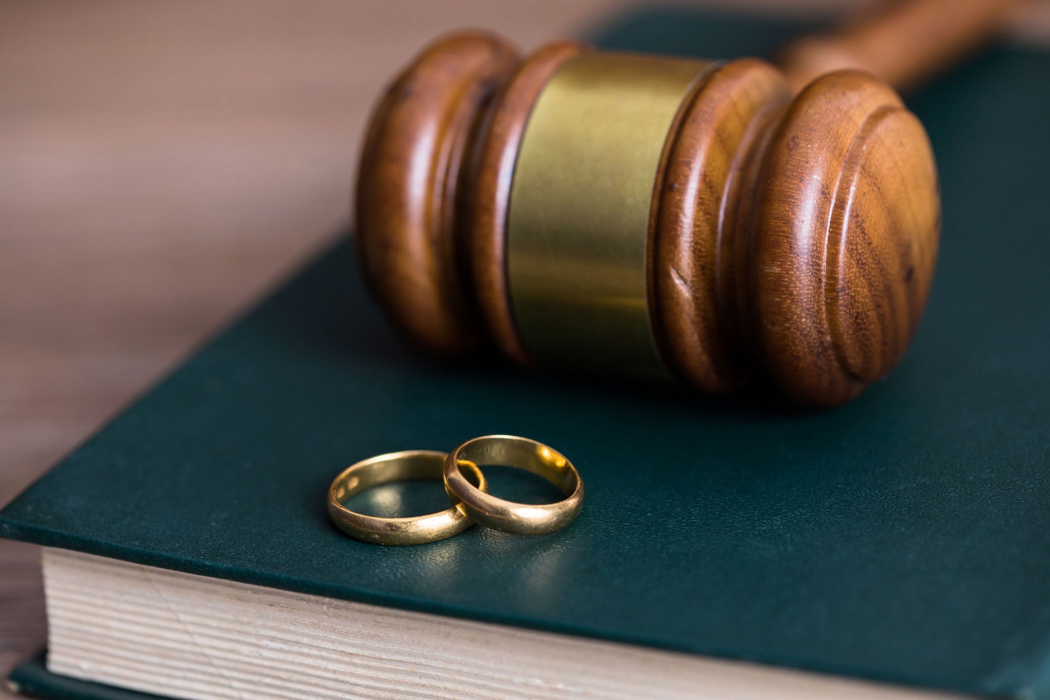 Anillos de matrimonio junto a un mazo sobre libro de derecho familiar